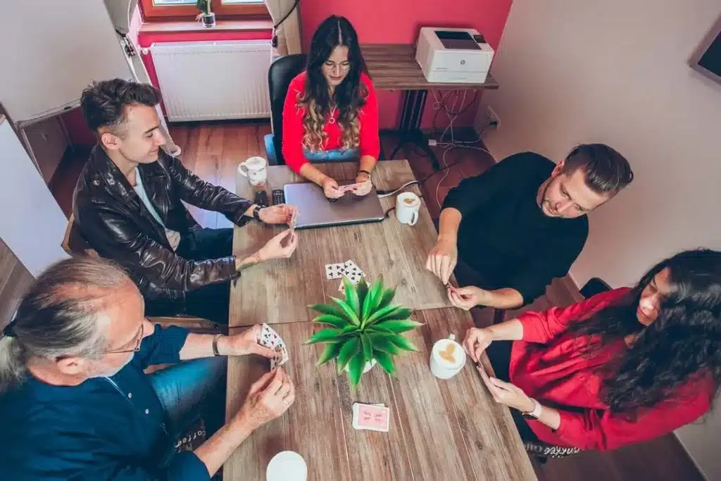 Öt résztvevő kártyákkal végez beszédgyakorlatot, miközben a Café English élőnyelvi módszere látszik.