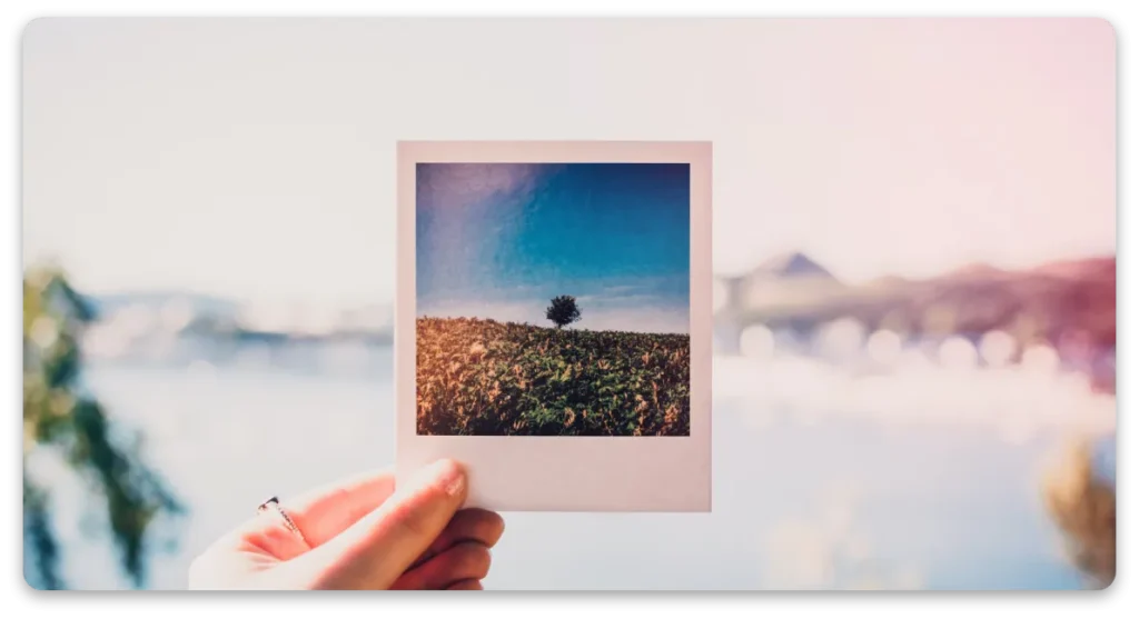 Egy kéz mezőt ábrázoló polaroidot tart, amely az Eredményes módszer – Élményalapú, Beszédközpontú Angol hangulatát idézi.