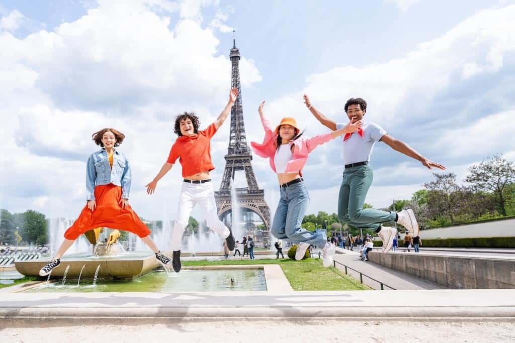 Vidám diákok ugranak az Eiffel-torony előtt, miközben a MÁTRIX vagy többoldalú angol oktatási modell hangulatát idézik.
